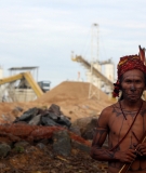 A lone warrior stands in front of the occupied construction site of the Belo Monte Dam in the Brazilian Amazon.