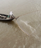 A man casts a fishing net into the Mekong River from a boat in Phnom Penh in December 2011.