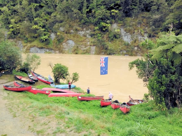 The muddy swollen river raced past the John Coull Hut, where about 40 of us recreational canoeists were stranded for the day as the government shut down river access. The New Zealand flag hangs above our encampment.