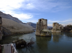(on the right) The Old Hasankeyf Bridge (on the left) the stone wall that seals the historical caves, which are now filled with debris.