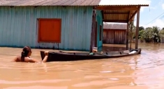 A woman navigates a boat through the flooded streets of Porto Velho, Brazil.