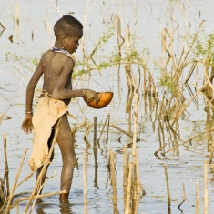 Boy filling gourd along Omo River