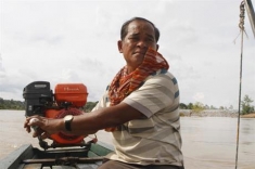 A Cambodian tourist boat owner drives his boat.