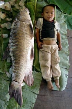 A Karen boy lies next to a fish caught in the Salween River.