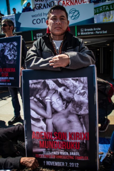 A Munduruku leader commemorates a murdered river defender while protesting at the 2019 World Hydropower Congress in Paris.