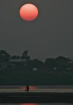A man walks along the Mekong River at sunset in Vientiane, Laos.